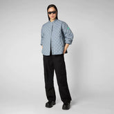 Model showcases a modern look with a light blue quilted SaveTheDuck jacket and relaxed black cargo pants, finished with bold black platform shoes and sleek sunglasses. | Save The Duck | Animal Free Elegant Duvets for Men and Women