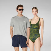 Man in gray t-shirt and navy blue swim trunks standing next to woman in green leaf-patterned one-piece swimsuit | Save The Duck | Animal Free Elegant Duvets for Men and Women