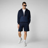 Man wearing navy blue recycled polyester hoodie and shorts with white sneakers | Save The Duck | Animal Free Elegant Duvets for Men and Women