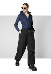 Woman wearing navy blue recycled polyester jacket with black wide-leg pants and sunglasses | Save The Duck